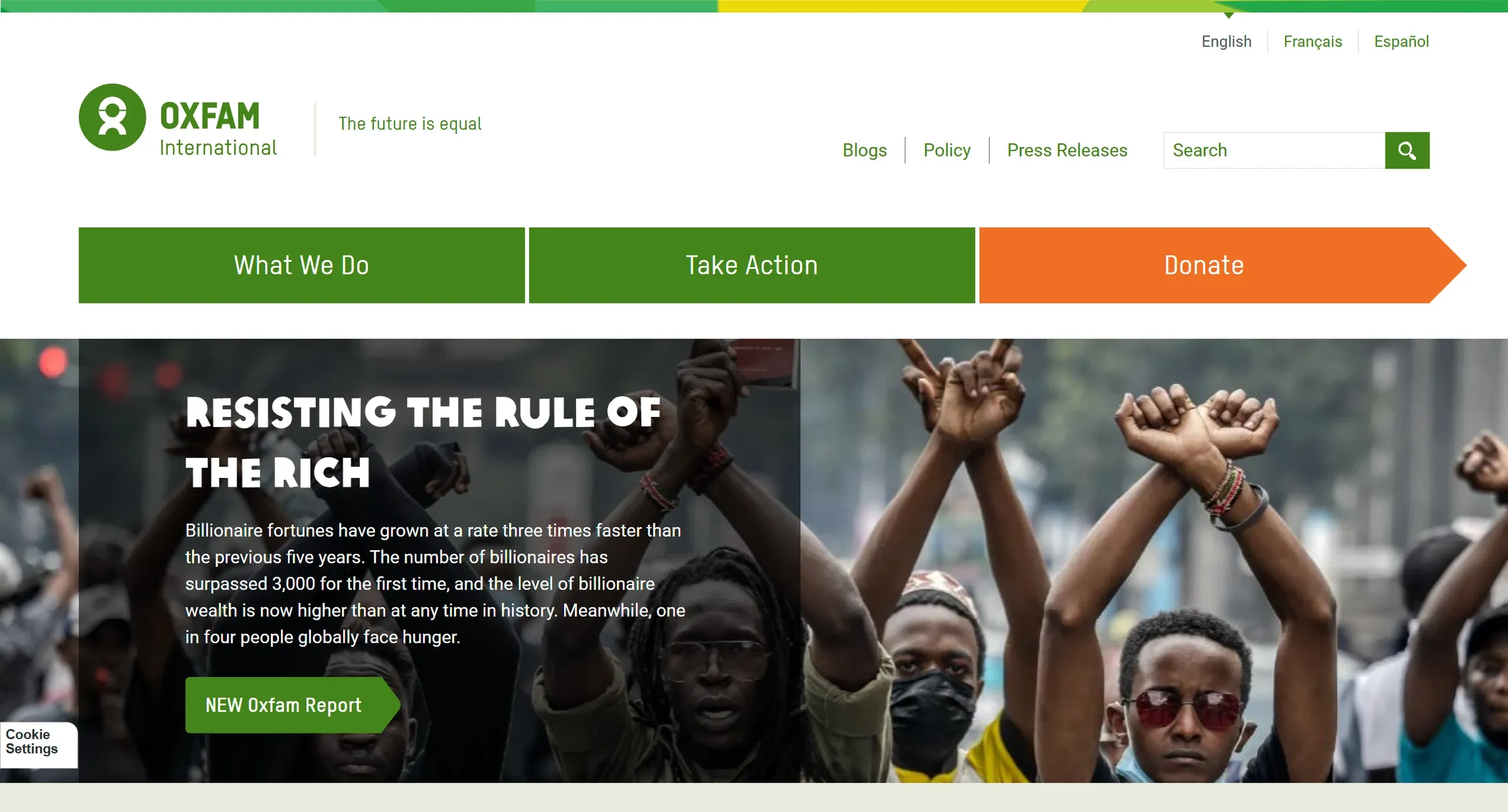Oxfam International's homepage, three full-width buttons above a report headline, and a three-language switcher at the top